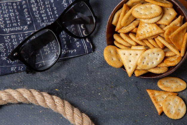 Free photo top view brown plate with crackers and ropes on the grey background crisp cracker photo snack