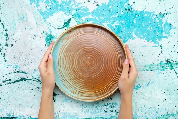 Free Photo top view of brown round mold hold by female on light-blue, cake food meal