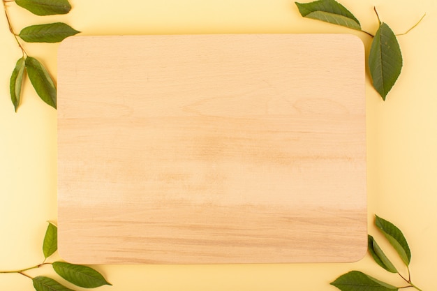 Free photo a top view brown wooden desk rustic along with green leaves apricot colored