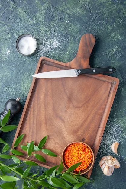 Top view brown wooden desk with orange lentils on the dark blue surface ancient cuisine color meat butcher kitchen knife food