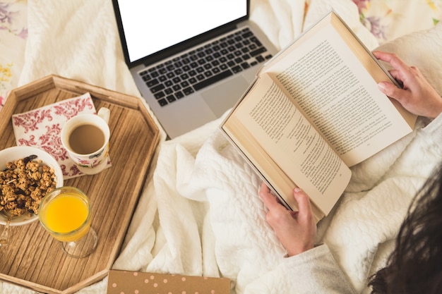 Top view of brunette woman with open book and laptop