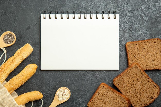 Top view of bun breads with dark bread loafs on dark grey surface