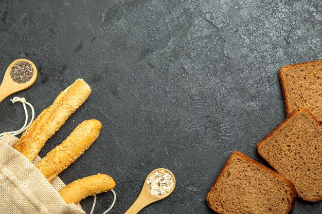 Top view of bun breads with dark bread loafs on grey surface