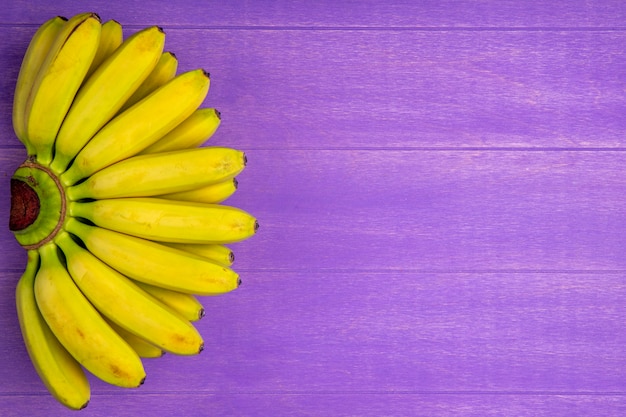 Free photo top view of bunch of bananas isolated on purple wood with copy space