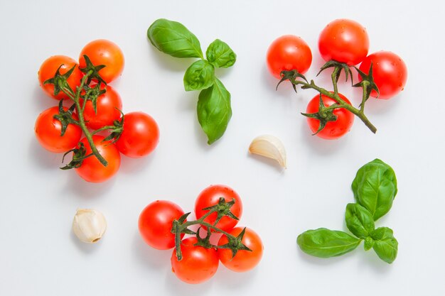 Top view bunches of tomatoes with garlic and leaves on white background. horizontal