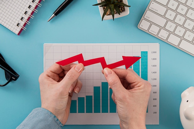 Top view of business items with growth chart and hands holding arrow