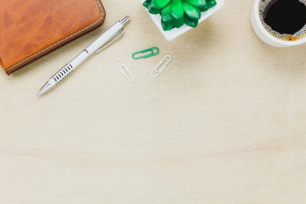 Top view business office desk.the notebook,pencil,black coffee,tree,paperclips on wooden table background.