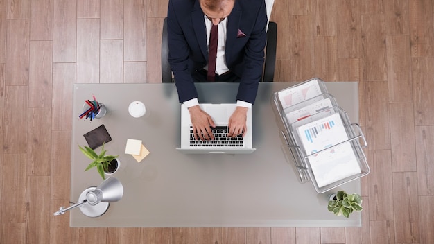 Top view of businessman typing management strategy on laptop analyzing company profit