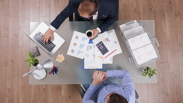 Free Photo top view of businessmen discussing company strategy analyzing marketing paperwork