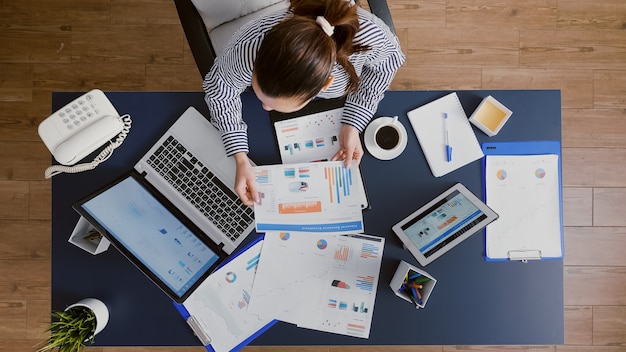 Top view of businesswoman sitting at desk table checking financial accounting documents