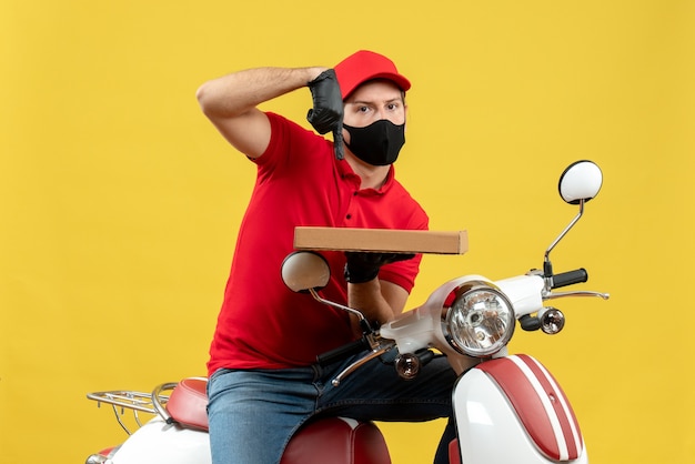 Top view of busy courier man wearing red blouse and hat gloves in medical mask sitting on scooter pointing order