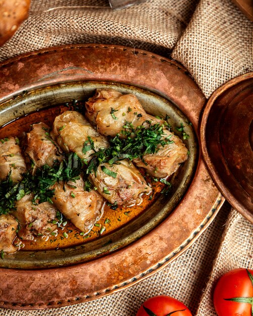 Top view cabbage rolls with herbs and tomatoes on the table