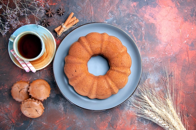 Top view a cake a cup of tea blue plate of cake cupcakes cinnamon star anise wheat ears