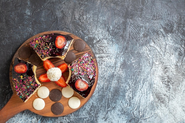 Top view cake slices with cookies on dark-light surface