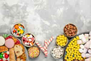 Free photo top view of cake slices with french macarons bagels and candies on white wall