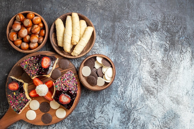 Top view cake slices with nuts and cookies on dark surface