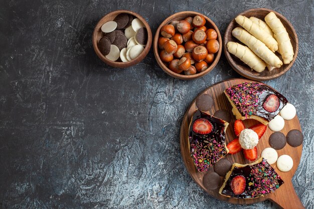 Top view cake slices with nuts and sweets on dark surface