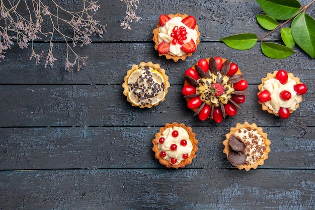 Free photo top view cake with cornel fruit raspberry and chocolate surrounded with tarts leaves on dark wooden table with copy space