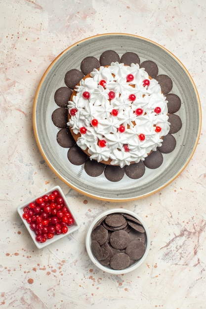 Top view cake with pastry cream and berries and chocolate in bowls