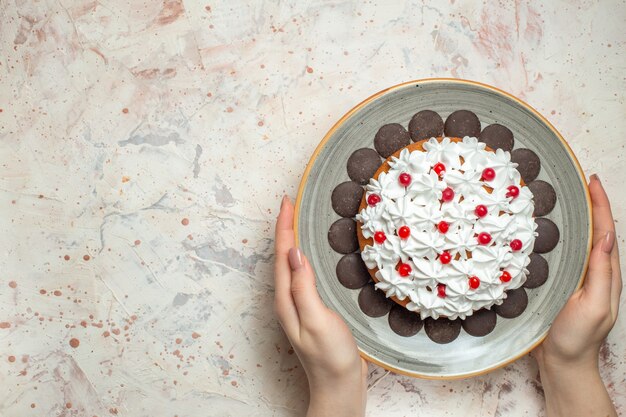 Top view cake with pastry cream and chocolate in female hand