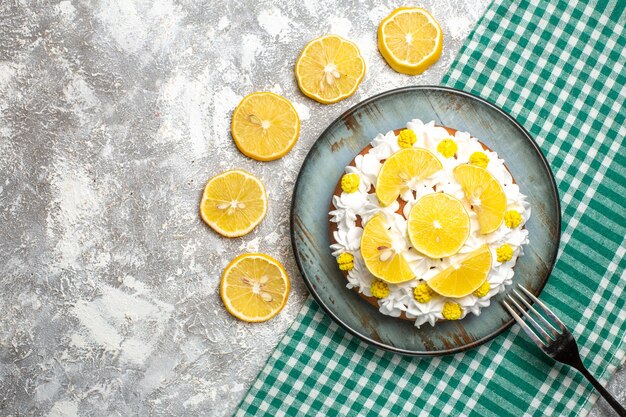 Top view cake with pastry cream and lemon fork on platter on green white checkered tablecloth