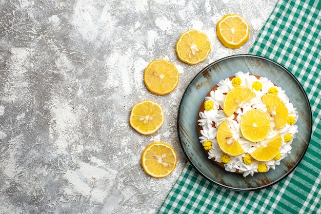 Top view cake with pastry cream and lemon on round platter on green white checkered tablecloth