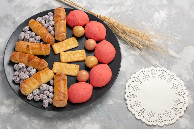 Free photo top view cakes and bagels with candies and crackers inside plate on white background cake biscuit cookie sugar sweet pie