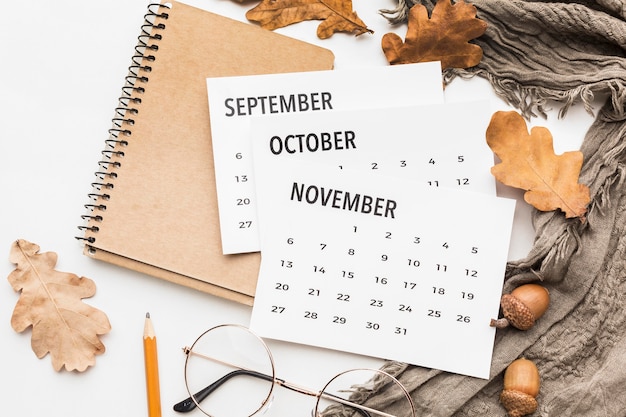 Top view of calendar with glasses and autumn leaves