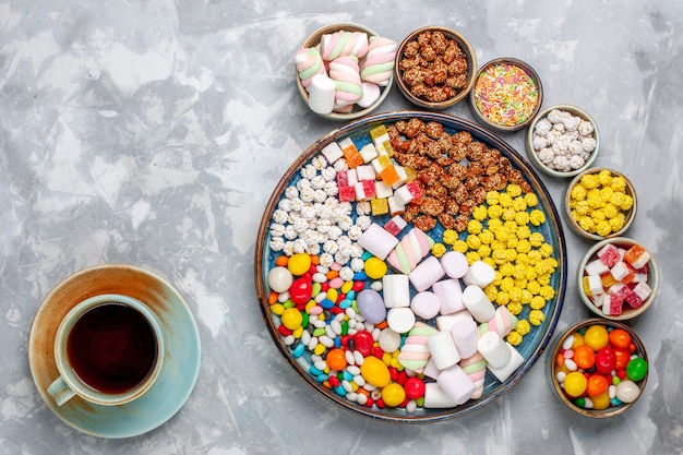 Free photo top view candy composition different colored candies with marshmallow inside pots with tea on white desk sugar candy bonbon sweet confiture