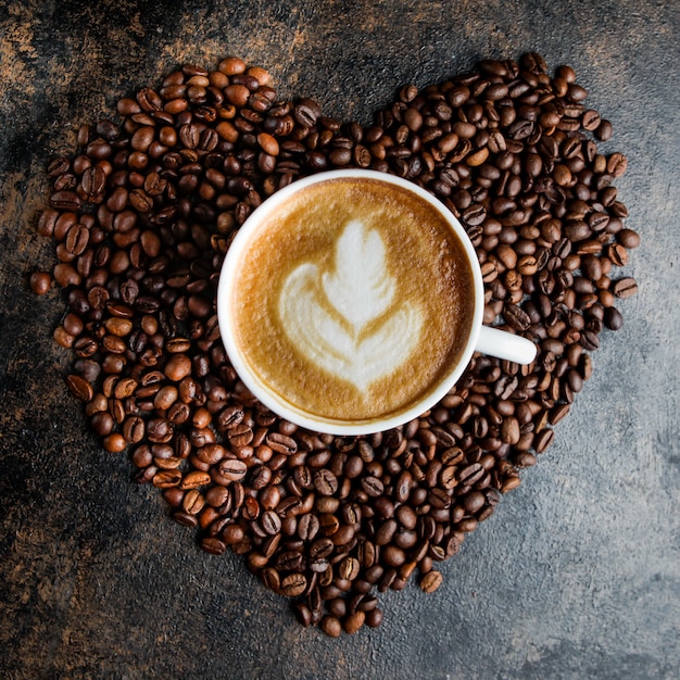 Top view cappuccino cup and coffee beans in the form of a heart