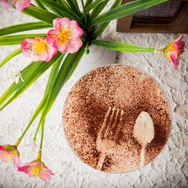 Top view cappuccino with the inscription with vase with flowers and napkin holder in cocktail glass