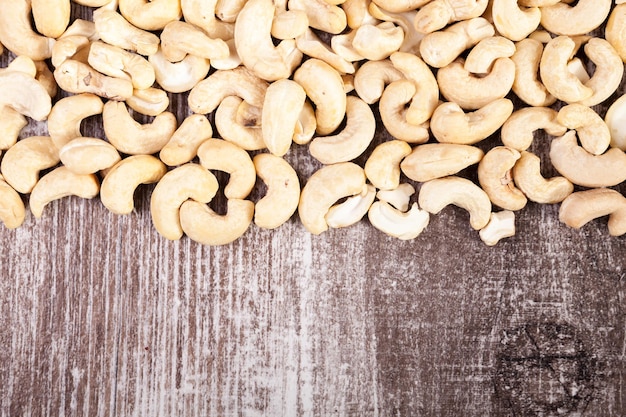 Free photo over top view of cashew nuts on wooden background in studio photo. raw healthy food