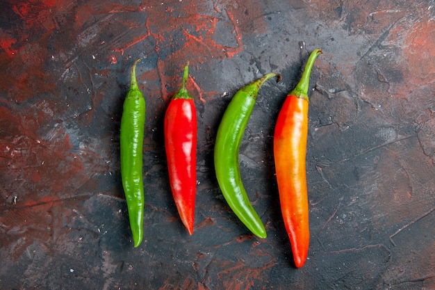 Free photo top view of cayenne peppers in different colors and sizes on mixed color background