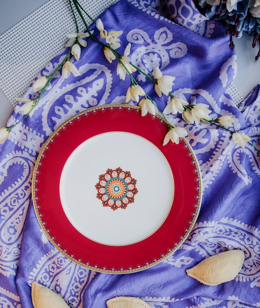 Free Photo top view of ceramic eastern plate with a national pattern on purple traditional kelagai silk female scarf wall