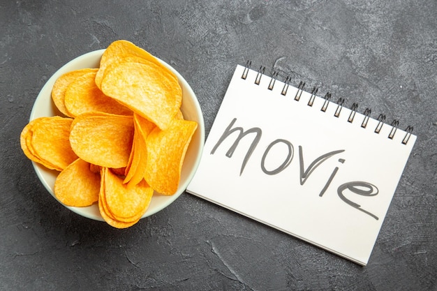 Free photo top view cheese cips inside plate with notepad and movie writing on it on dark background