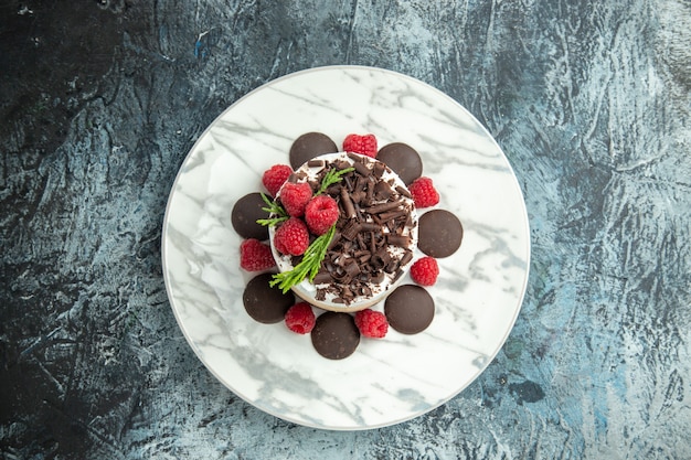 Top view cheesecake with chocolate on white oval plate on grey surface free space