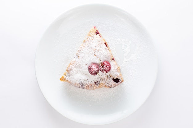 Top view cherry cake slice inside white plate with sugar powder on the white background cake biscuit sweet dough bake