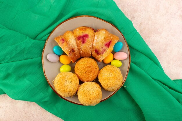 Free Photo a top view cherry cake slices with candies and biscuits on the pink desk cake biscuit sweet