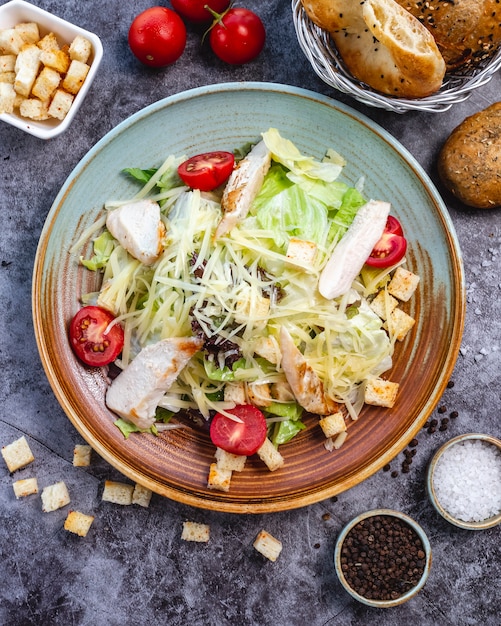 Top view of chicken caesar salad with lettuce cherry tomato bread stuffing and parmesan