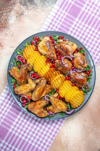 Top view of chicken chicken potatoes herbs onion on the checkered tablecloth