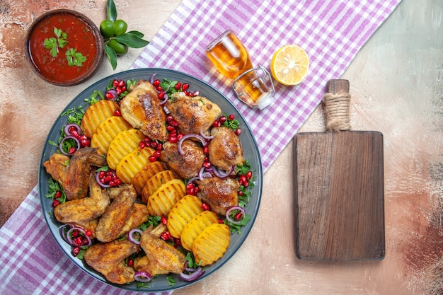 Free photo top view chicken chicken wings potatoes lemon oil on the tablecloth next to the cutting board