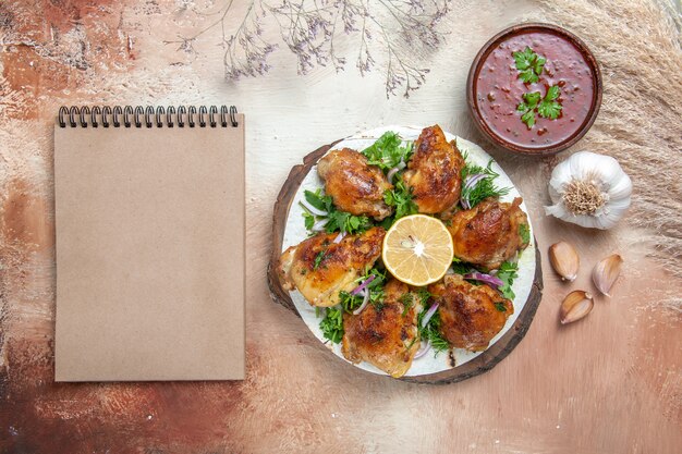 Top view chicken chicken with herbs lemon garlic sauce next to the cream notebook