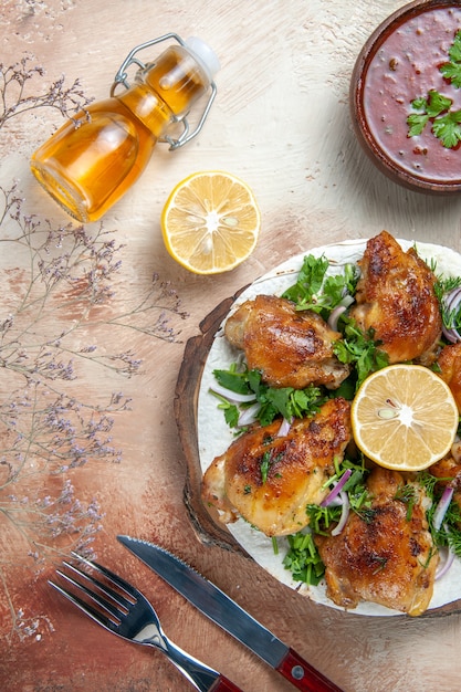 Free photo top view of chicken garlic bottle of oil lemon sauce chicken with herbs on lavash fork knife