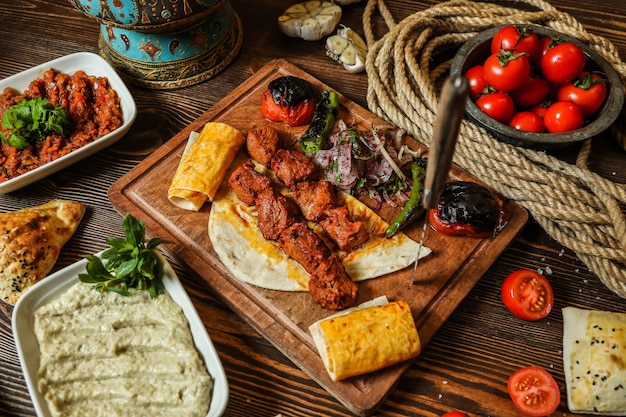 Top view chicken kebab with grilled tomato and hot pepper on pita bread on a stand