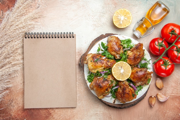 Free photo top view of chicken oil tomatoes garlic lemon chicken with herbs cream notebook