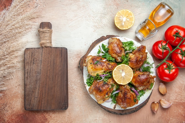 Free photo top view of chicken oil tomatoes garlic lemon chicken with herbs the cutting board