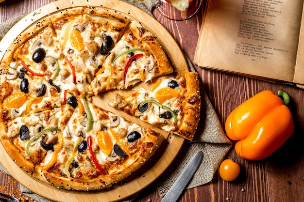 Top view chicken pizza with yellow cherry tomatoes and bell pepper on the board