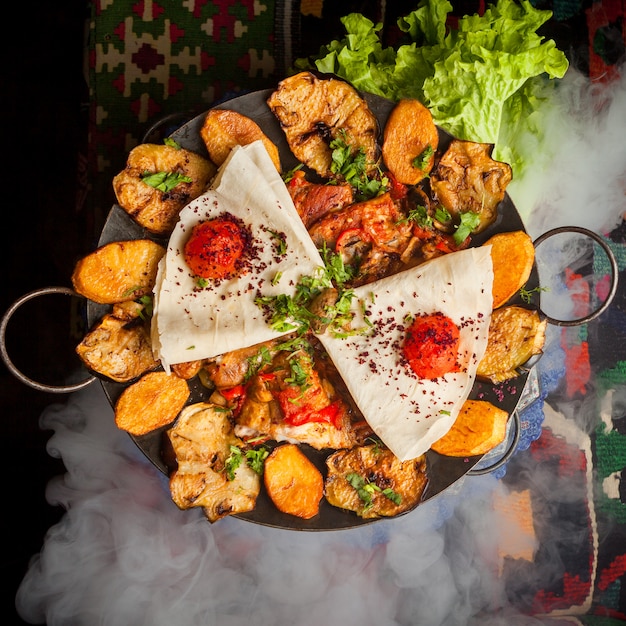 Free photo top view chicken sac with fried potatoes and tomato and lavash in smoke