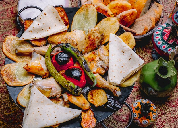 Top view chicken sage with potatoes vegetables and pita bread