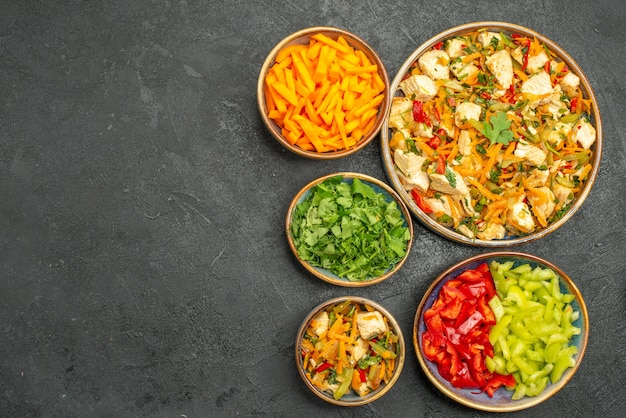 Top view chicken salad with vegetables on the dark-grey table diet health salad